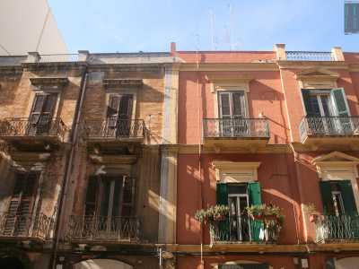 Foto 2. Siamo in via Quintino Sella, all�altezzza di via Principe Amedeo. Notiamo sin da subito un primo e caratteristico contrasto che ci accompagner� per tutto il resto del nostro viaggio. Si tratta di due edifici adiacenti praticamente uguali: ma mentre il primo, marroncino, appare quasi abbandonato, il secondo invece si presenta con un acceso e sfavillante color salmone e con dei fiori a ornare le ringhiere dei balconi 
